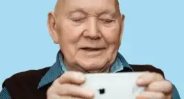 Photo shows older man looking at a moble phone, cutout on blue background