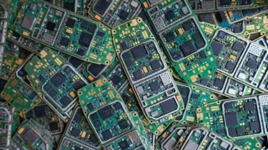 Top shot of a pile of mobile phone circuit boards, cutout on blue background